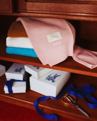 木桌上Burberry钱夹和卡片夹照片，打开的抽屉里装满了Burberry格纹围巾