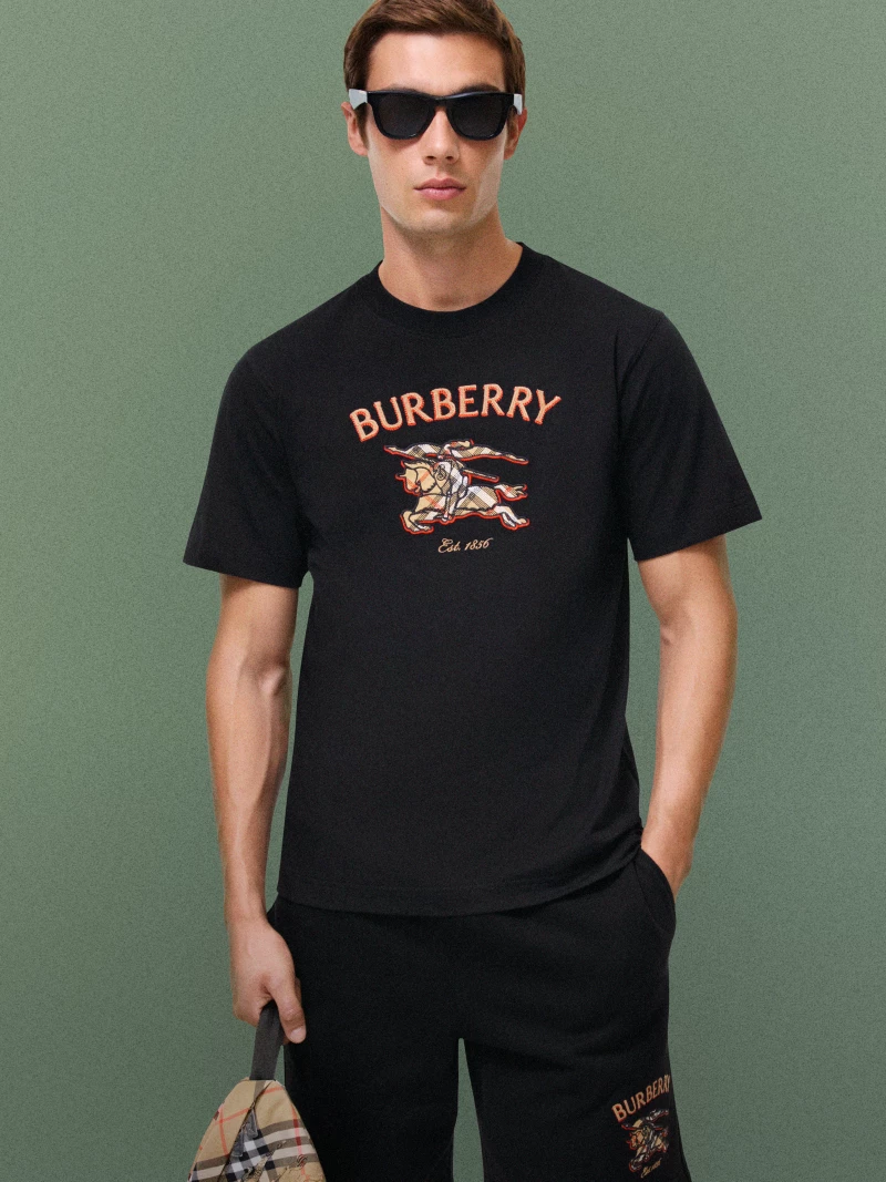模特佩戴深色太阳眼镜，身穿Burberry徽标图案黑色T恤衫