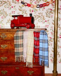 木质抽屉照片，第一个抽屉里露出四条Burberry格纹围巾，抽屉顶部放着一个玩具火车