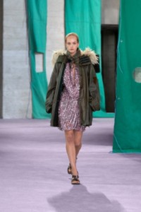 Model wearing trim waxed cotton parka in oil and metallic paillette fringed viscose jersey dress in lilac.