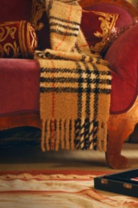 红色丝绒椅上放有Burberry格纹羊绒围巾的照片 