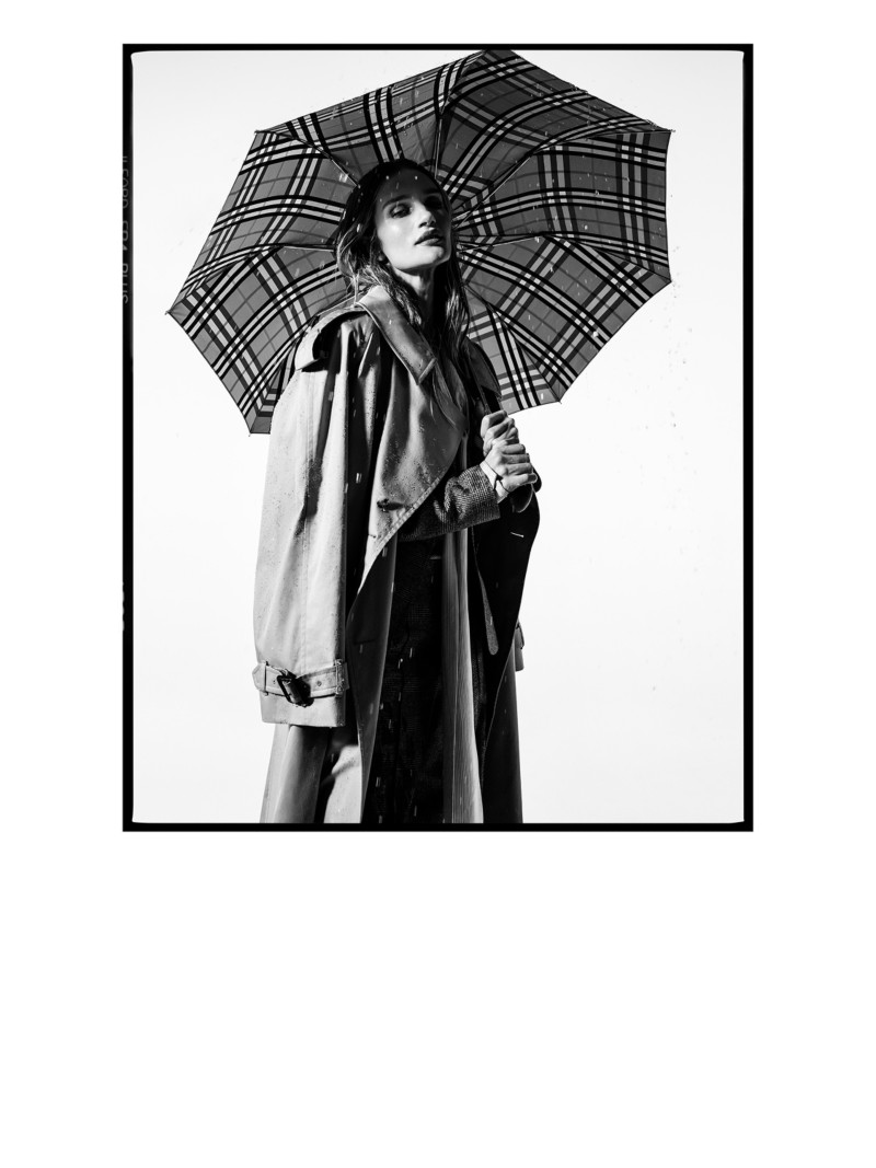 模特Rosie Huntington-Whiteley身穿Burberry卡斯尔福德版型长款风衣，手持Burberry格纹雨伞