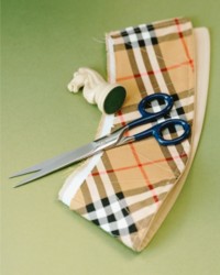 Burberry格纹面料特写，上面放着一把剪刀和一枚国际象棋马棋子 