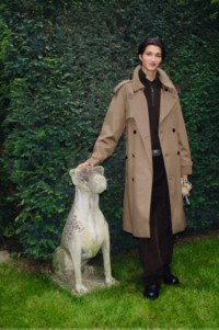 图片中，模特身穿长款Burberry风衣，靠在萌犬石像旁