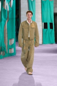 Model wearing cotton canvas jacket and cargo trousers in walrus, with Embroidered EKD cotton piqué polo shirt in salt.